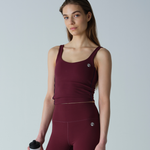 Woman wearing a maroon athletic outfit holding a white water bottle on a light gray background
