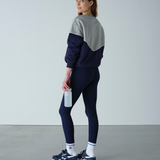 Person wearing a two-tone sweatshirt and leggings set, holding a water bottle against a plain background.