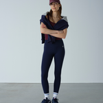 Woman wearing a navy outfit with a maroon cap against a plain background