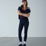 Woman wearing a navy outfit with a maroon cap against a plain background