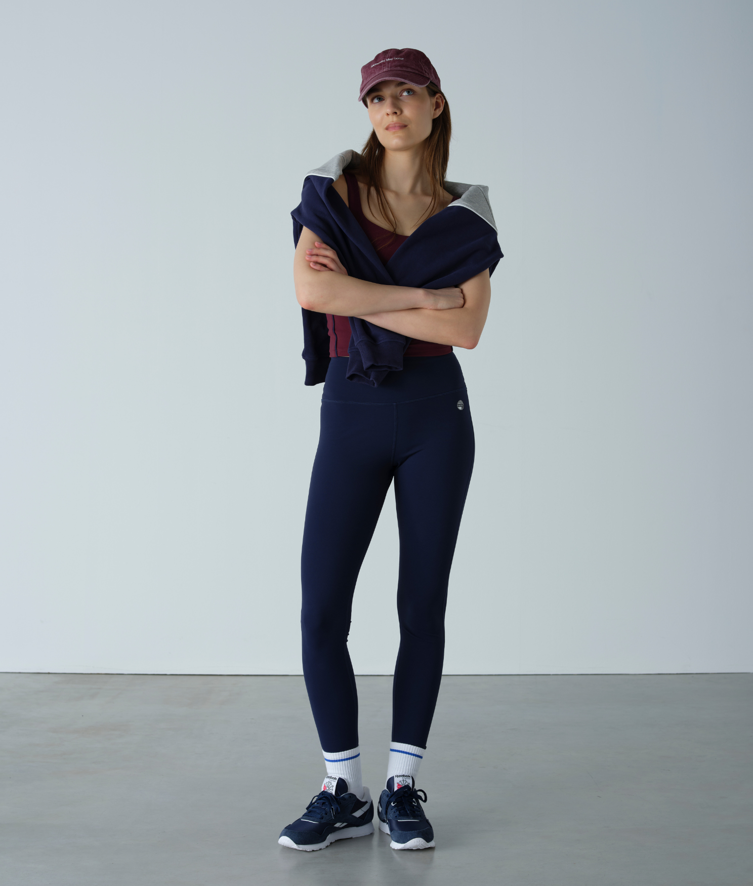 Woman wearing a navy outfit with a maroon cap against a plain background