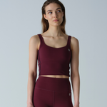 Woman wearing a maroon athletic outfit on a light gray background