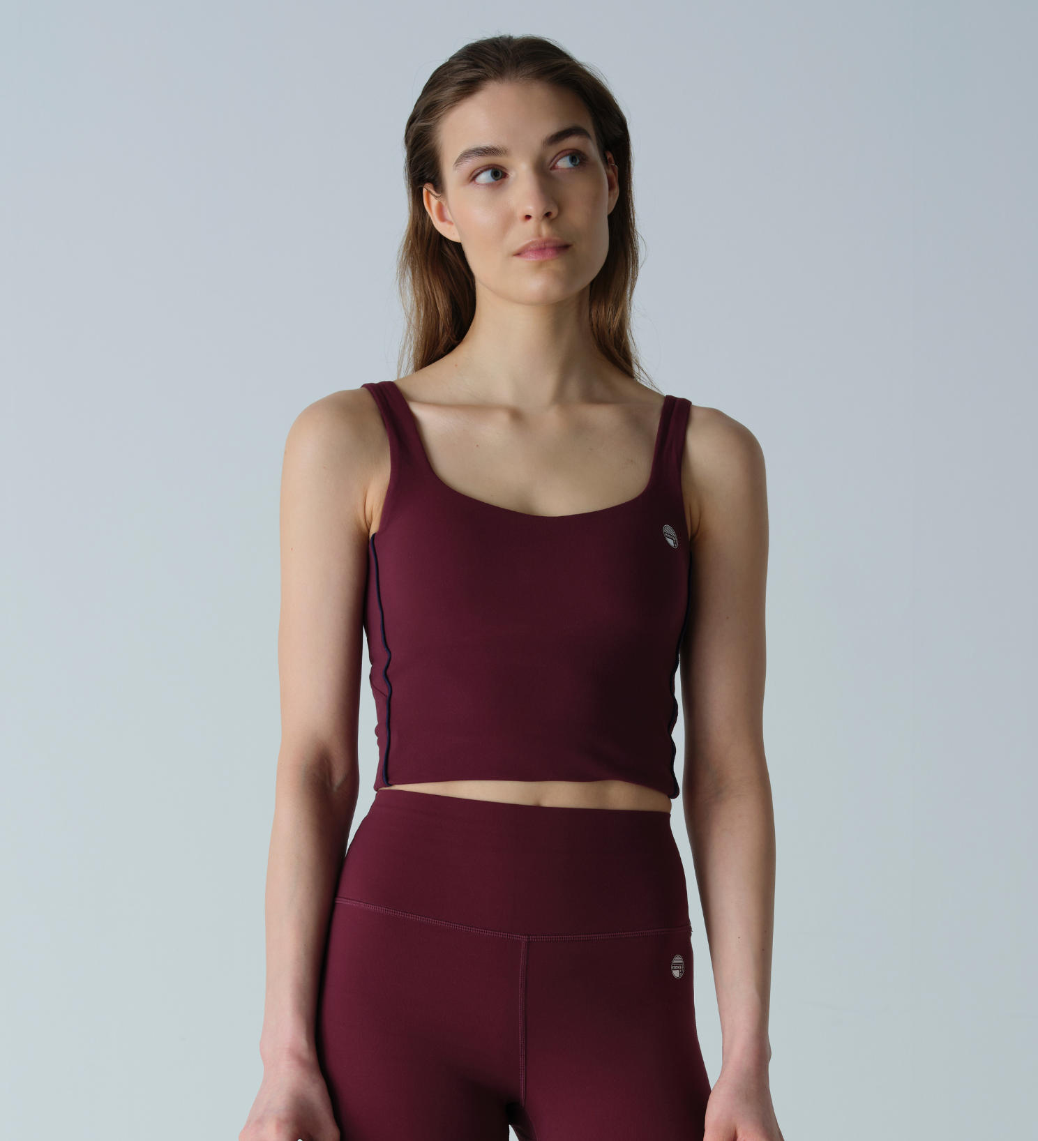 Woman wearing a maroon athletic outfit on a light gray background