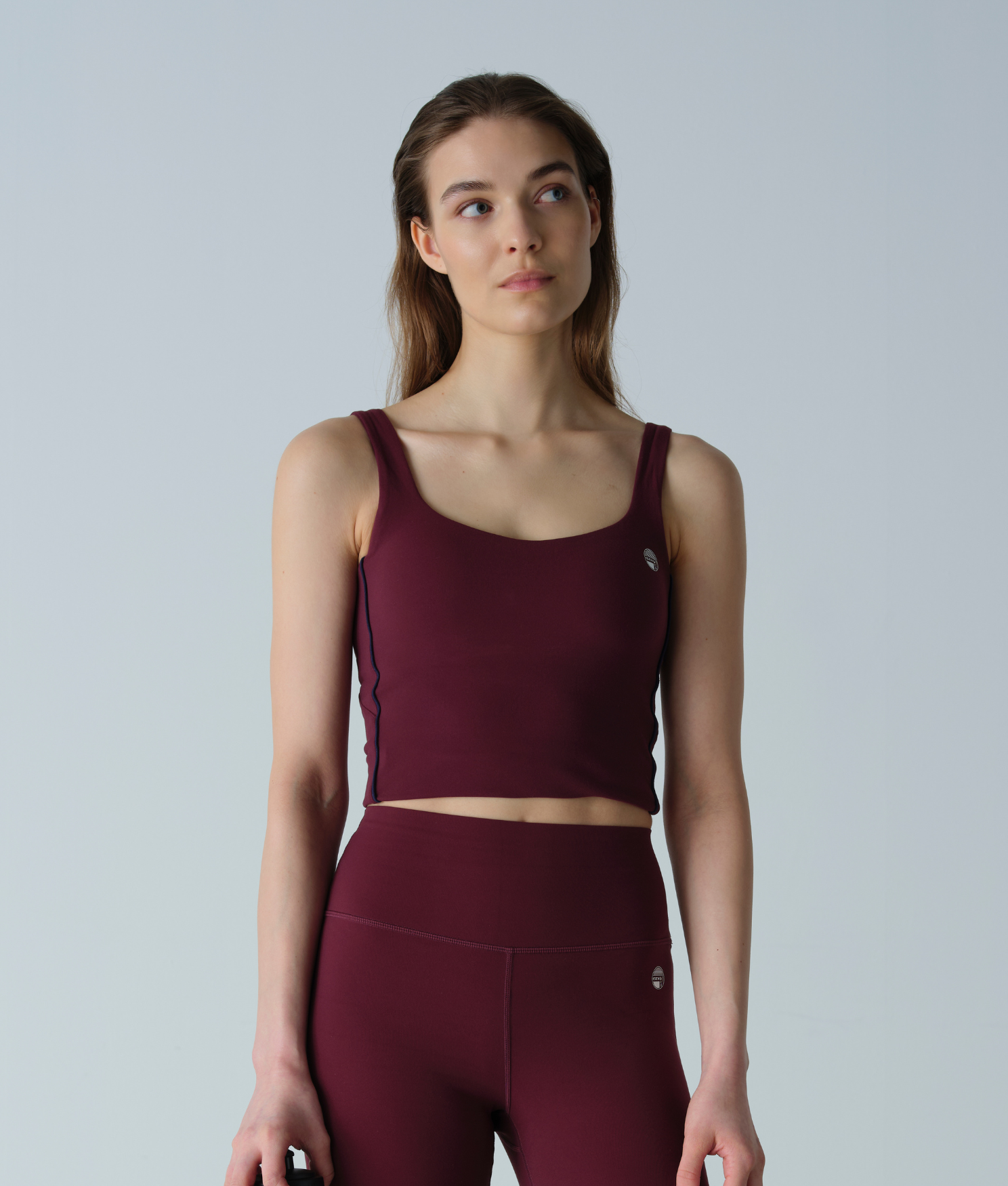 Woman wearing a maroon athletic outfit on a light gray background