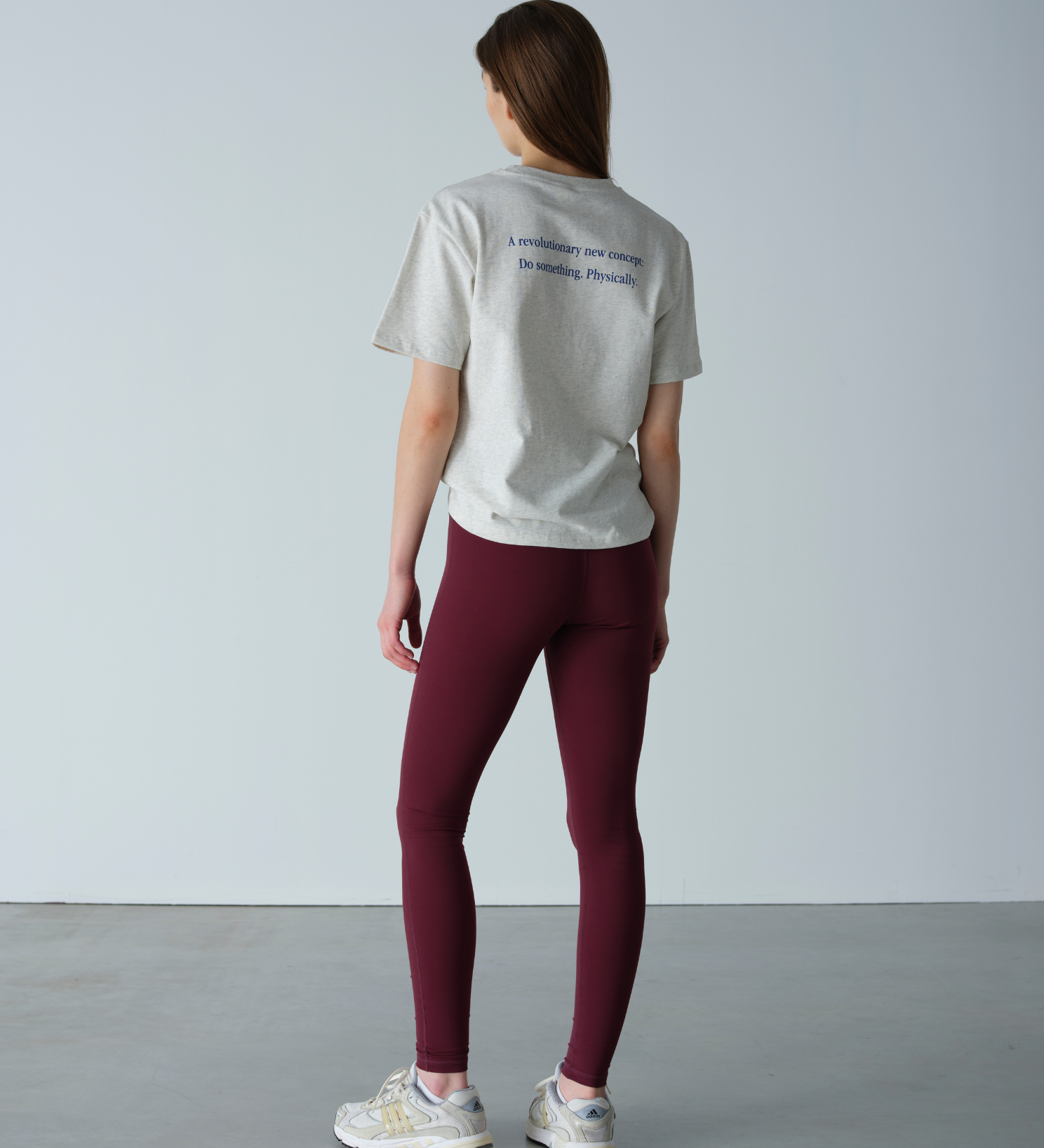 Person wearing a light gray t-shirt and maroon leggings against a plain background