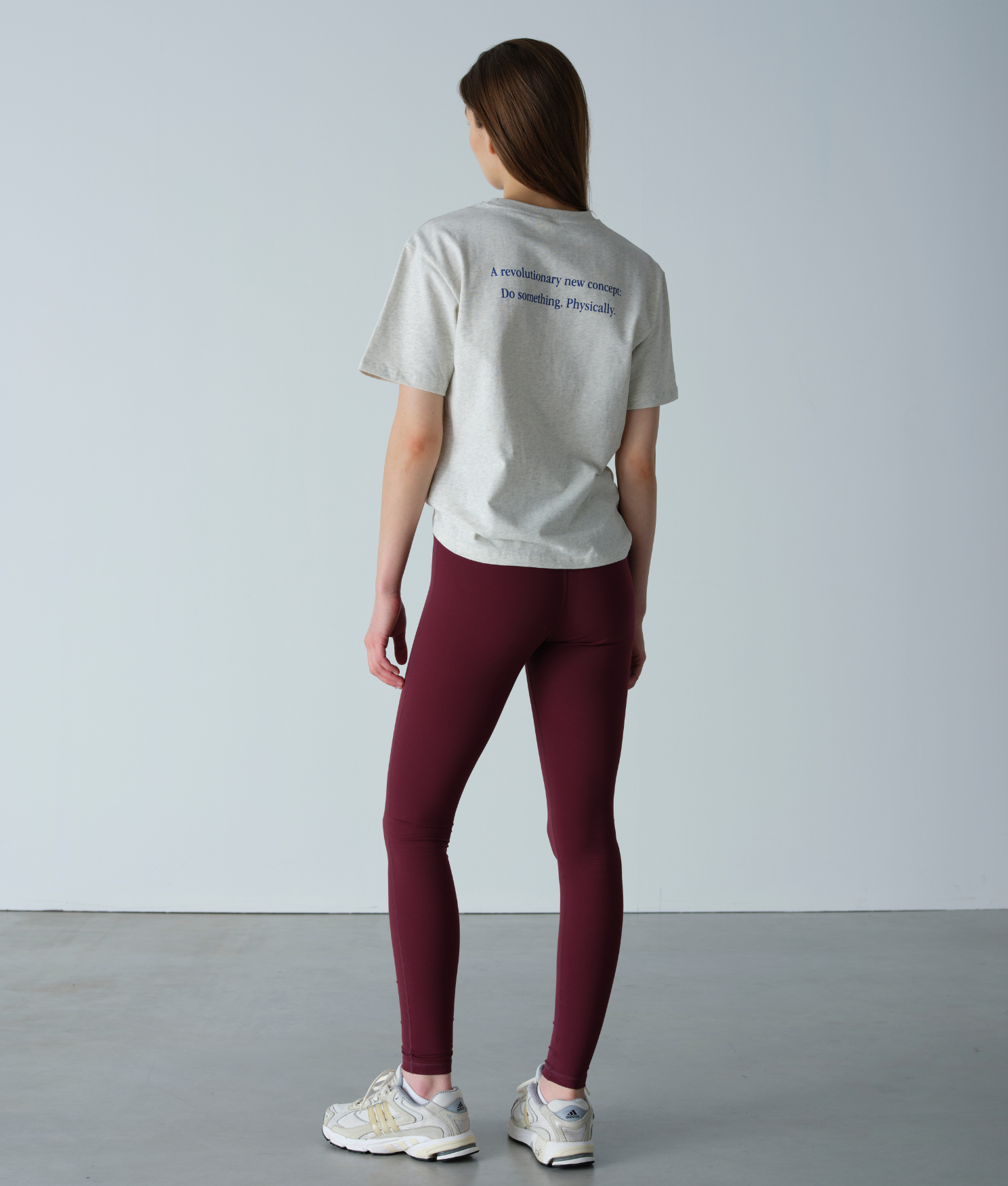 Person wearing a light gray t-shirt and maroon leggings against a plain background