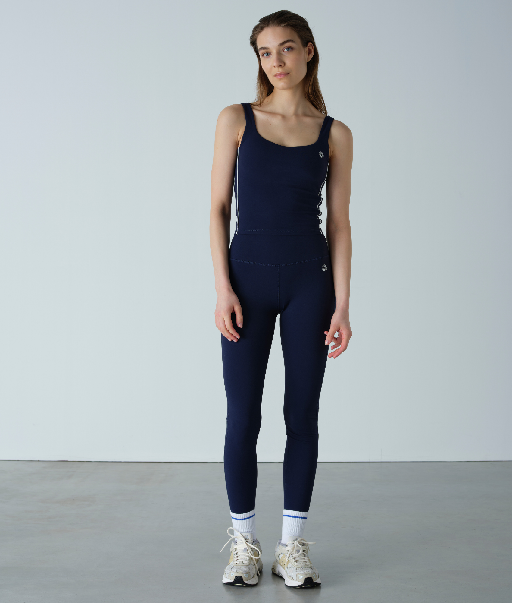 Woman wearing a navy blue sleeveless top and leggings set against a plain background