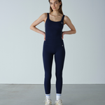 Woman wearing a navy blue jumpsuit against a plain background