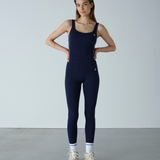 Woman wearing a navy blue jumpsuit against a plain background