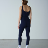 Person wearing a navy blue jumpsuit against a plain background